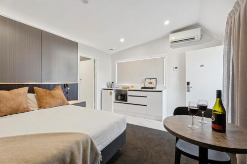 a bedroom with a bed and a table with wine glasses at Sai Motels - Greenlane Auckland in Auckland