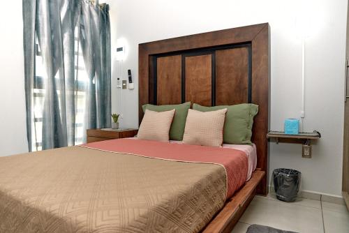 a bedroom with a large bed with a wooden headboard at Casa Los Tules No 10 in Ciudad Guzmán
