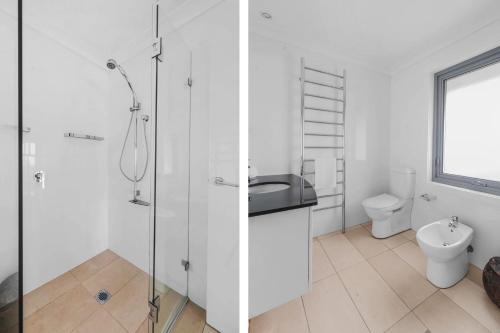 a white bathroom with a shower and a toilet at Surfbreak, Culburra Beach in Culburra Beach