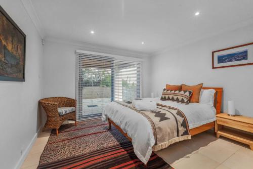 a white bedroom with a bed and a window at Surfbreak, Culburra Beach in Culburra Beach