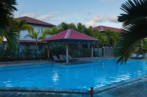 a large blue swimming pool with a gazebo at Le Cottage 61 - Au Bonheur de Sophie in Le Vauclin