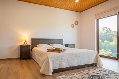 ein Schlafzimmer mit einem Bett und einem großen Fenster in der Unterkunft Casas de São Pedro in Rio Caldo