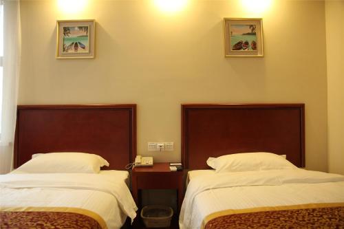 a room with two beds and a table with a phone at GreenTree Inn Shanghai Outlets National Convention Centre XuLe Road Shell Hotel in Qingpu
