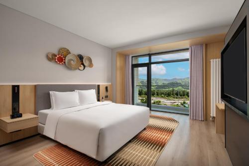 a bedroom with a white bed and a large window at Holiday Inn Express Nalati By IHG in Narat