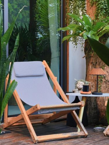 a wooden lounge chair on a patio with a table at Salad Beach Guest House in Ko Phangan