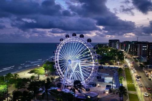 a ferris wheel in a city near the ocean at Pousada Maceio é Massa Pajuçara Frente ao Mar in Maceió