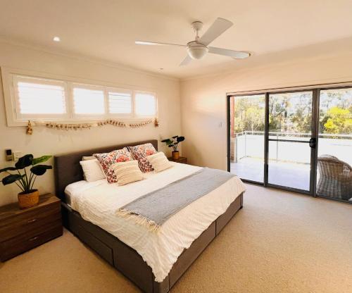 a bedroom with a bed and a ceiling fan at Oasis by the Bay - 4 bedroom Beach House in Corlette