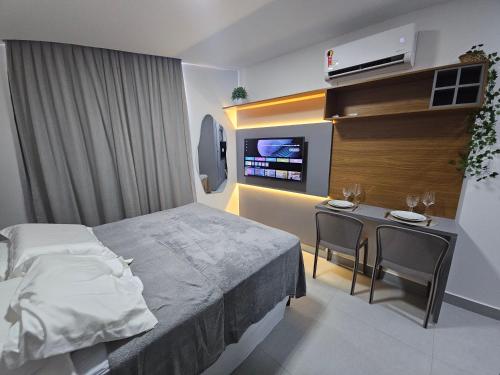 ein Schlafzimmer mit einem Bett, einem Tisch und einem Fernseher in der Unterkunft Lindo Flat em Manaíra no Solaz in João Pessoa