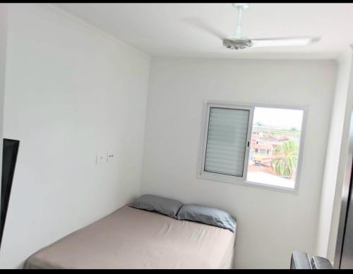 Un dormitorio pequeño con una cama y una ventana. en Apartamento Mirim Praia Grande, en Praia Grande