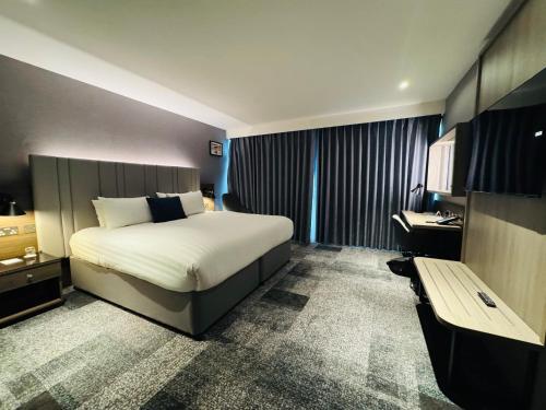a hotel room with a bed and a bench at Crowne Plaza London - Kingston by IHG in Kingston upon Thames