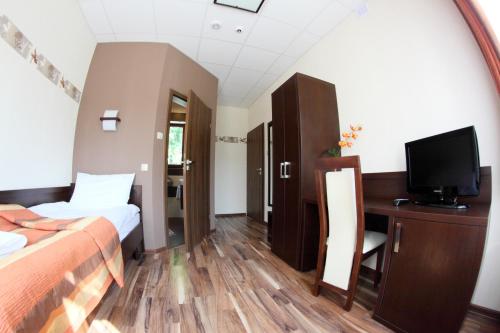 a hotel room with a bed and a desk with a television at Hotel Mieszko in Rzeszów
