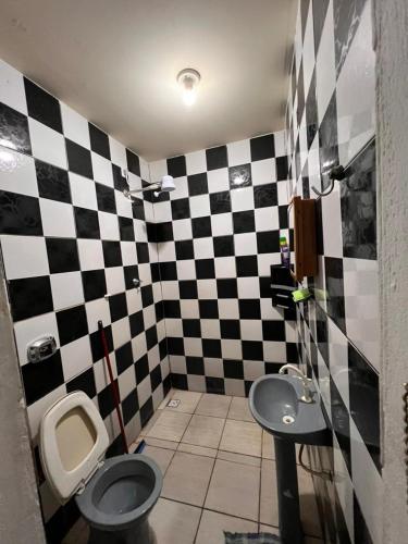 um banheiro xadrez com um vaso sanitário e uma pia em Casa próximo a UFR - QUARTO SALA E COZINHA EQUIPADA em Rondonópolis