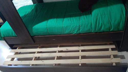 un letto con un lenzuolo verde sopra di Departamento 1ambiente a metros de la playa Zona Centro a Mar del Plata
