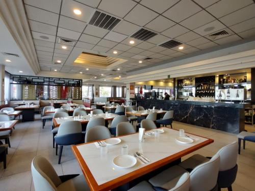 墨西卡利克罗尼尔墨西卡利酒店的有桌椅和酒吧的餐厅