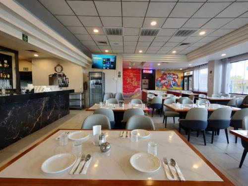 墨西卡利克罗尼尔墨西卡利酒店的有桌椅和酒吧的餐厅