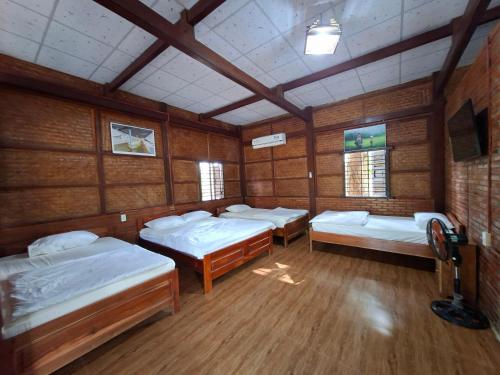 a room with four beds and a tv in it at Cát Tiên Riverside in Tân Phú