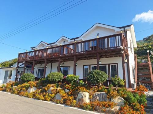 a house with a balcony on the side of it at Yeosu Geumodo Badaae Pension in Yeosu