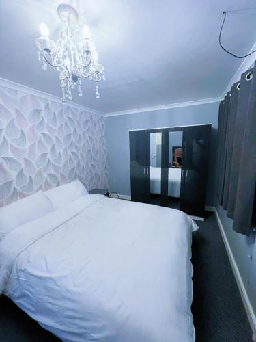 una camera da letto con un letto bianco e un lampadario di Mona a Hull