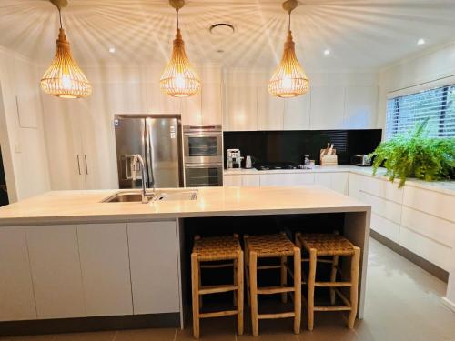 a kitchen with a sink and a counter with stools at Oasis by the Bay - 4 bedroom Beach House in Corlette