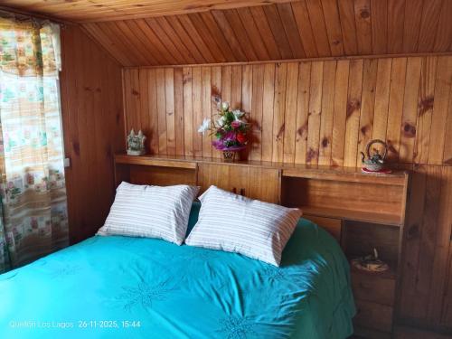 a bedroom with a bed in a wooden room at Hospedaje Mirador del Puerto in Quellón