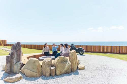 a group of people sitting on a rock fountain next to a motorcycle at Lady Blue伊豆稲取 in Higashiizu