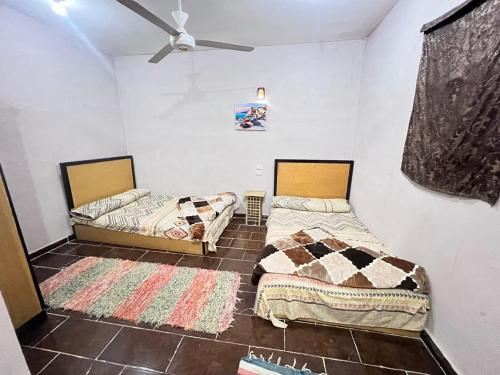 a room with two beds and a ceiling fan at Hotel Dakrour-فندق الدكرور in Siwa