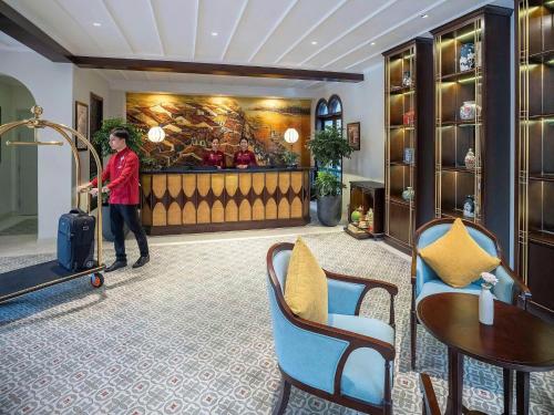 a woman with a suitcase in a hotel lobby at Little Residence - A Boutique Hotel & Spa in Hoi An