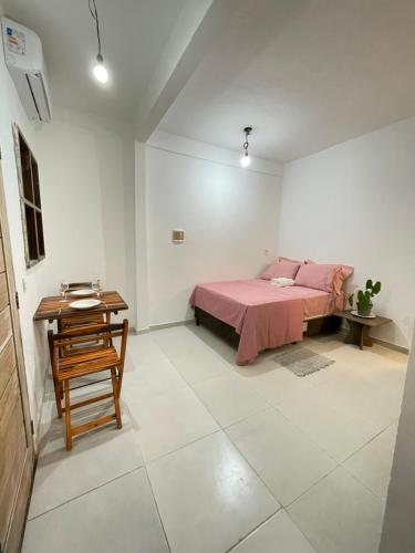 a bedroom with a pink bed and a table at Mini Kitnet-Caraíva- Nova caraiva in Caraíva