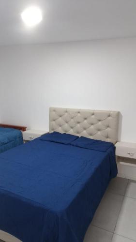 a bedroom with a blue bed and a white wall at Macarena in La Falda