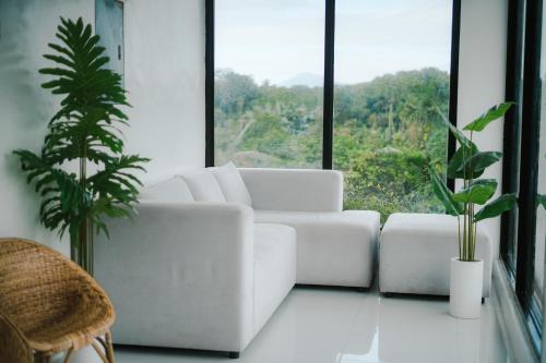 ein Wohnzimmer mit weißem Sofa und großem Fenster in der Unterkunft Villa Soledad Garden Resort in Sampong