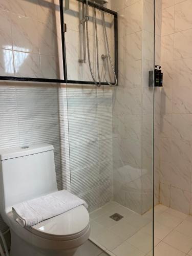 a bathroom with a toilet and a glass shower at Crystal Resort Korat in Nakhon Ratchasima