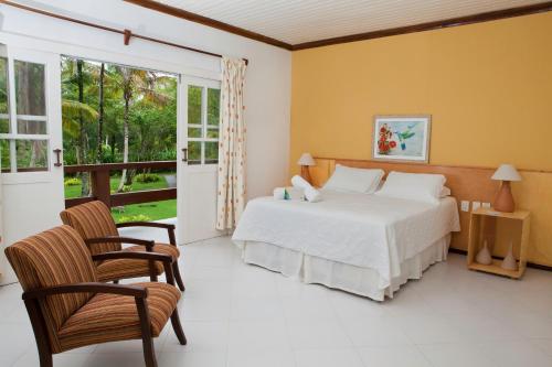 a bedroom with a bed and two chairs at Hotel Karapitangui in Morro de São Paulo