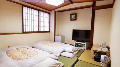 a room with two beds and a flat screen tv at Hotel Sakuranbo in Yamagata