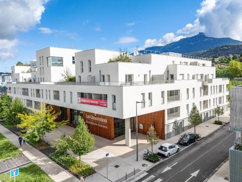 尚贝里Quality Suites Chambéry的街道上的白色建筑,前面有停车位