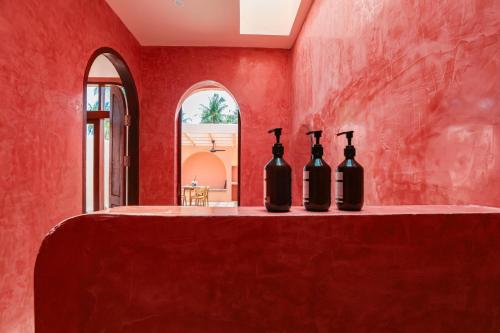 Drei Flaschen Wein stehen auf einem Tisch in einem roten Zimmer in der Unterkunft Villa Solea in Gili Trawangan