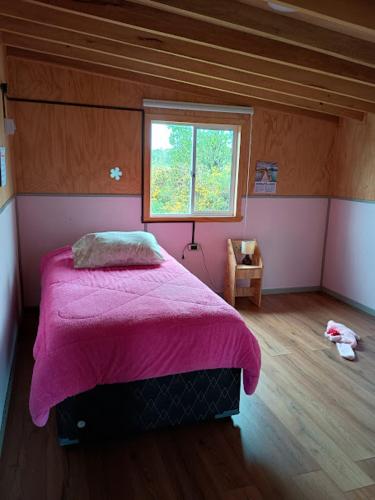 a bedroom with a pink bed and a window at Casa de Campo in Ancud