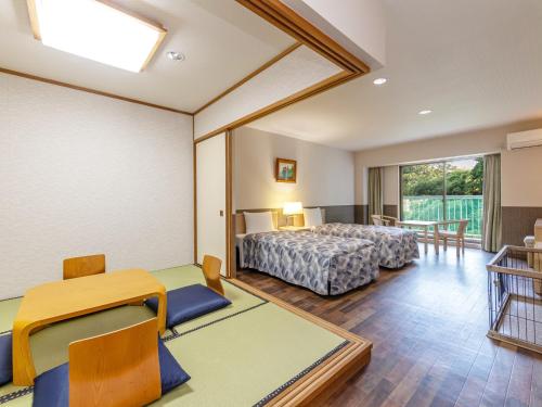 伊東市にあるAMBIENT 伊豆高原 コンドミニアムのベッドとテーブルと椅子のある寝室