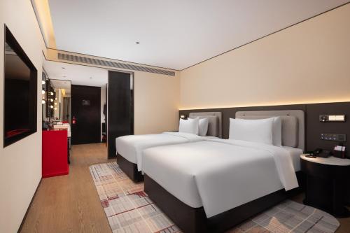 ein Hotelzimmer mit zwei Betten und einem Fernseher in der Unterkunft Radisson Blu Hotel Wuhan Jianghan Road Pedestrian Street in Wuhan