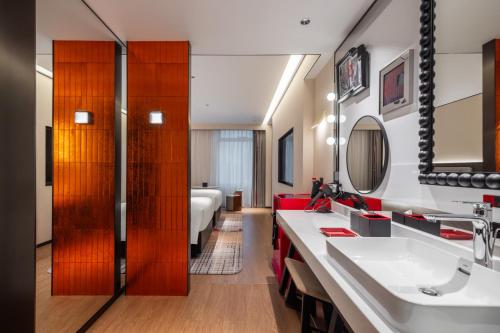 ein Badezimmer mit einem Waschbecken und ein Wohnzimmer in der Unterkunft Radisson Blu Hotel Wuhan Jianghan Road Pedestrian Street in Wuhan