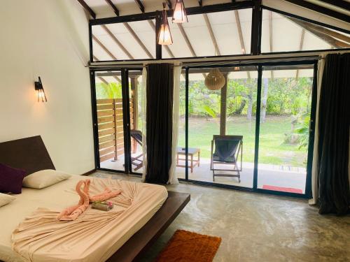 a bedroom with a bed in a room with sliding glass doors at Neem Jay Beach Resort in Tangalle