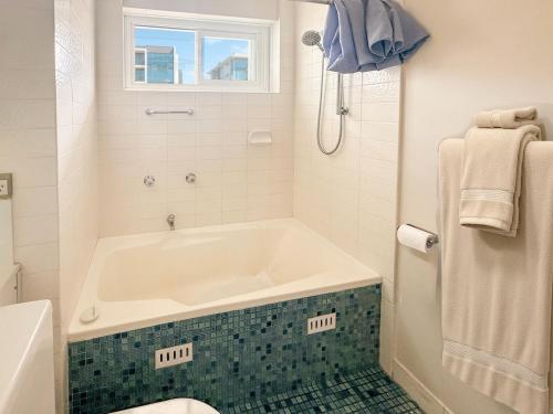 a white bathroom with a tub and a toilet at 150m to Dee Why Beach in Deewhy