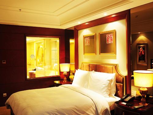 a bedroom with a bed and two lamps and a mirror at Dynasty International Hotel Dalian in Jinzhou