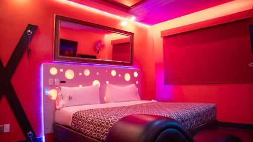 a bedroom with a bed with a mirror and pink lights at Hotel Muy Cdmx, Love Hotel in Mexico City
