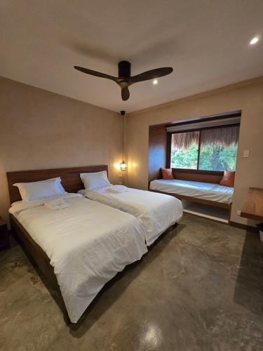a bedroom with a large bed with a ceiling fan at Kāpena Siargao in General Luna