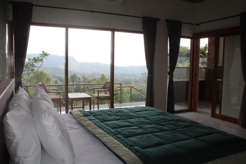 een slaapkamer met een bed en een balkon met ramen bij Rumah Bagus Jayanti in Sidemen