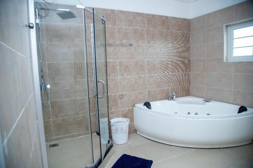 a bathroom with a tub and a glass shower at Nkrabea Royal Apartment in Trofwi