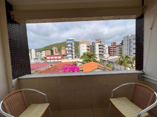 a view of a city from a window with two chairs at Apt Praia Mansa Don in Matinhos