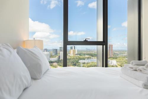 a white bed with a view of a city at SkyHaus - City & Fireworks View 2 Bed Apartment in Sydney