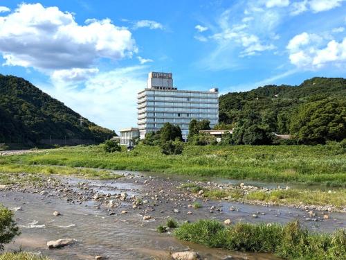 a building on a hill next to a river at Misasa Royal Hotel in Misasa