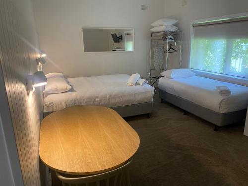 a room with two beds and a table and a window at Billabong Wangaratta in Wangaratta